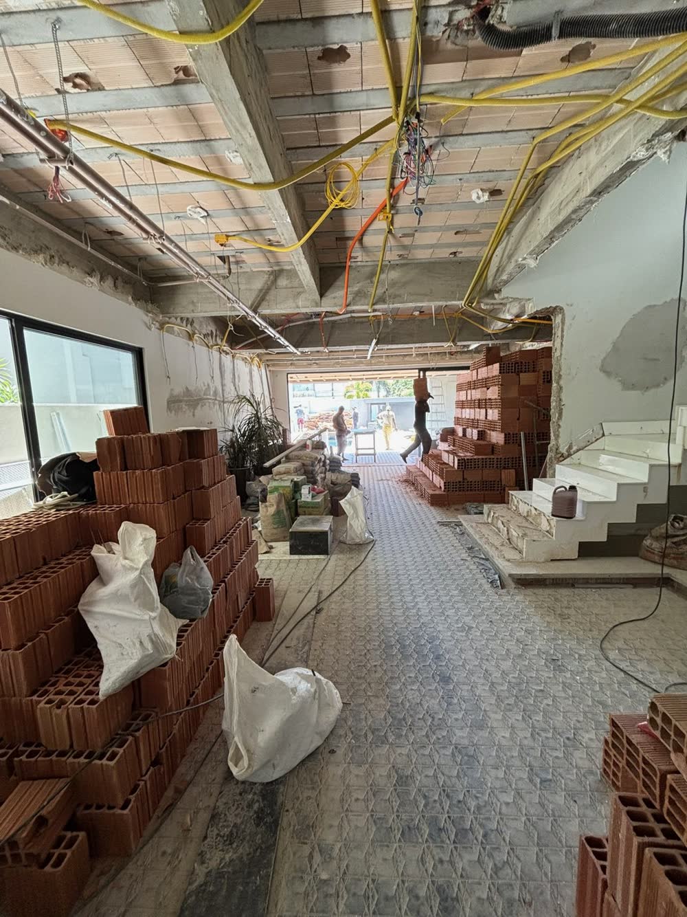 Obra em andamento com tijolos e argamassa sobre o piso protegido